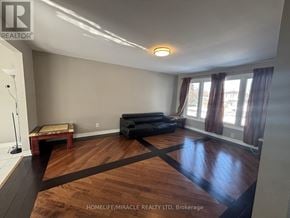 Brampton (Brampton South) apartment for rent - A living room with wooden floors and a black couch.