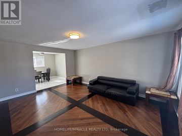 Brampton (Brampton South) apartment for rent - A living room with a black couch and wooden floors.