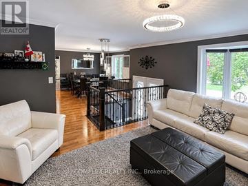 Oshawa (Centennial) apartment for rent - A living room with a white couch and a black ottoman.