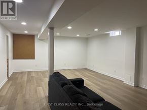 Innisfil (Alcona) apartment for rent - A room with a black couch and wooden flooring.