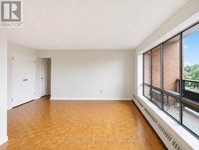 Mississauga (Applewood) condo for rent - A room with wooden floors and a large window with a view of trees.