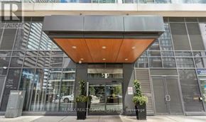 Mississauga (City Centre) condo for rent - The front of a building with a glass facade and a wooden overhang.