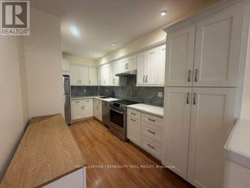 Toronto (St. Andrew-Windfields) townhouse for rent - A kitchen with white cabinets and a wooden floor.
