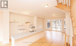 Oakville (Jm Joshua Meadows) townhouse for rent - A spacious kitchen with white cabinets and a wooden staircase.