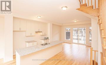 Oakville (Jm Joshua Meadows) townhouse for rent - A spacious kitchen with white cabinets and a wooden staircase.