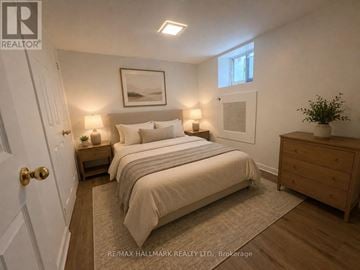 Toronto (South Riverdale) triplex for rent - A bedroom with a bed, nightstands, and a plant.