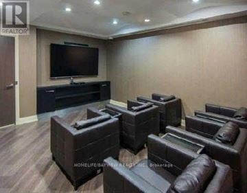 Vaughan (Beverley Glen) condo for rent - A living room with a dark brown leather couch and a flat screen TV mounted on the wall.