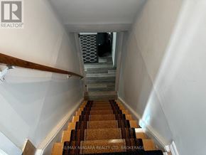 St. Catharines (Port Weller) apartment for rent - A staircase with a wooden handrail and a carpeted runner.