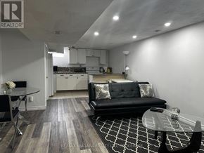 St. Catharines (Port Weller) apartment for rent - A modern living room with a black couch and a glass table.