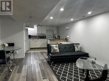 St. Catharines (Port Weller) apartment for rent - A modern living room with a black couch and a glass table.