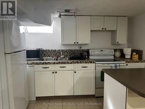 St. Catharines (Port Weller) apartment for rent - A kitchen with white cabinets and a black and white checkered backsplash.