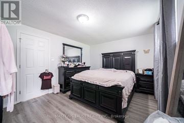 Oshawa (Farewell) apartment for rent - A bedroom with a dark wood bed and a white door.