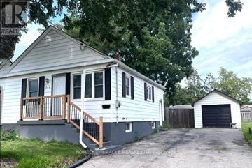Oshawa (Central) apartment for rent - A house with a grey siding and a white garage door is for sale.