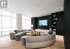 Brampton (Fletcher's Creek South) condo for rent - A modern living room with a large grey sofa and a television on the wall.
