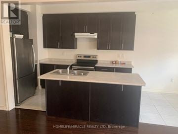 Brampton (Northwest Brampton) townhouse for rent - A kitchen with black cabinets and a stainless steel refrigerator.