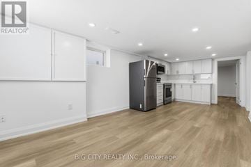 Oshawa (Vanier) multi-family for rent - A spacious kitchen with white cabinets and a wooden floor.