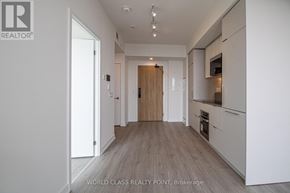 Mississauga (Mississauga Valleys) condo for rent - A hallway with wooden floors and white walls leading to a kitchen area.