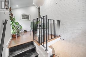Toronto (Roncesvalles) duplex for rent - A white brick wall with a black railing and a potted plant.