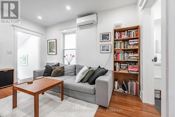 Toronto (Roncesvalles) duplex for rent - A living room with a grey couch, a coffee table, and a bookshelf filled with books.