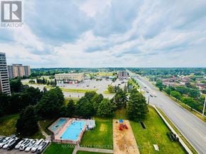 Brampton (Queen Street Corridor) condo for rent - A bird's eye view of a swimming pool surrounded by a grassy area and a parking lot.