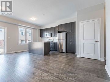 Hamilton (Ryckmans) townhouse for rent - A spacious kitchen with dark wood cabinets and a stainless steel refrigerator.