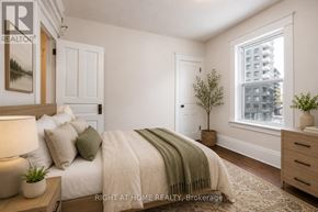 Kitchener multi-family for rent - A bedroom with a bed, nightstand, and window.