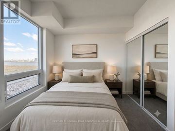 Toronto (Humber Heights) condo for rent - A bedroom with a large bed and a view of the outdoors through a window.
