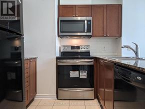 Mississauga (City Centre) condo for rent - A kitchen with a black fridge, black oven, and brown cabinets.