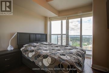 Mississauga (City Centre) condo for rent - A bedroom with a large bed and a view of the city.