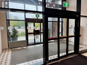 Toronto (Junction Area) condo for rent - A glass door with a black frame and a green exit sign above it.