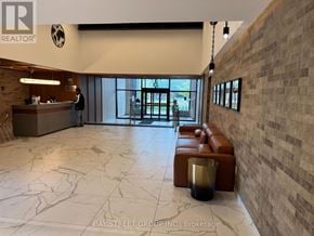 Toronto (Junction Area) condo for rent - A reception area with a brick wall and a person standing by the window.