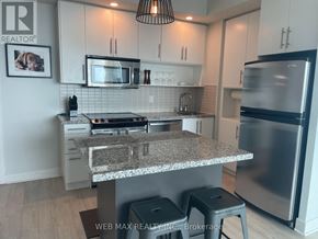 Toronto (North St. James Town) condo for rent - A kitchen with a granite countertop and stainless steel appliances.