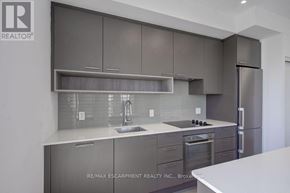 Oakville (Wm Westmount) condo for rent - A modern kitchen with a stainless steel refrigerator and a white countertop.