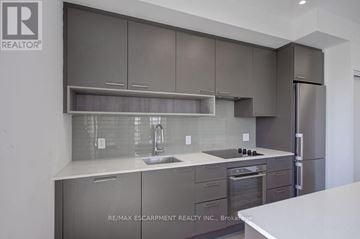 Oakville (Wm Westmount) condo for rent - A modern kitchen with a stainless steel refrigerator and a white countertop.