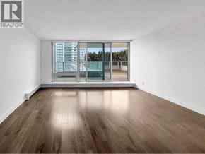 Vancouver apartment for rent - A room with wooden flooring and a large window overlooking a building.