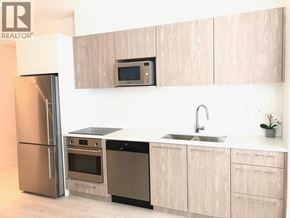 Coquitlam apartment for rent - A modern kitchen with a stainless steel refrigerator and a microwave above the stove.