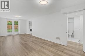 Hamilton apartment for rent - A spacious room with wooden flooring and white walls, featuring a kitchenette and a bathroom.