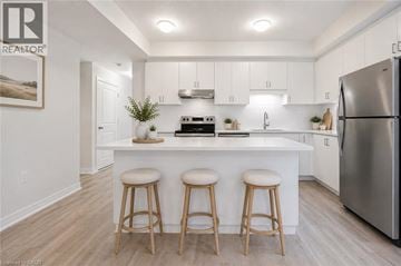 Kitchener townhouse for rent - A kitchen with white cabinets and a white island with a refrigerator on the right.