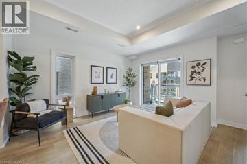Kitchener townhouse for rent - A living room with a sofa, a chair, a rug and pictures on the wall.