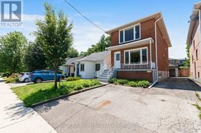 Toronto (Long Branch) apartment for rent - A blue car is parked in front of a two-story house with a white garage door.