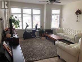 Oakville (Go Glenorchy) townhouse for rent - A living room with a white couch, a brown coffee table, and a ceiling fan.