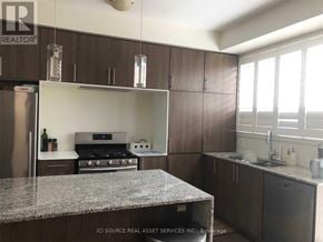 Oakville (Go Glenorchy) townhouse for rent - A kitchen with a granite countertop and wooden cabinets.