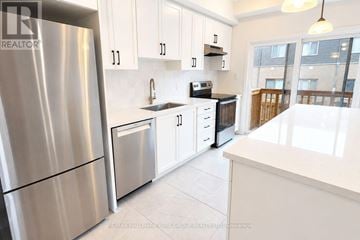 Barrie townhouse for rent - A modern kitchen with white cabinets and a stainless steel refrigerator.
