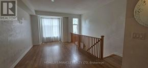 Oshawa (Donevan) townhouse for rent - A spacious room with wooden floors and a large window with white curtains.