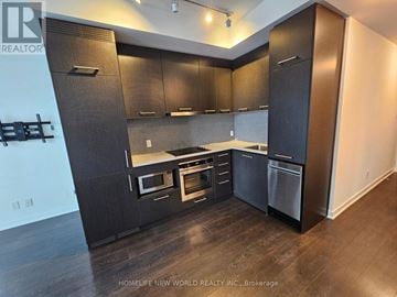 Toronto (Waterfront Communities) condo for rent - A modern kitchen with dark wood cabinets and stainless steel appliances.