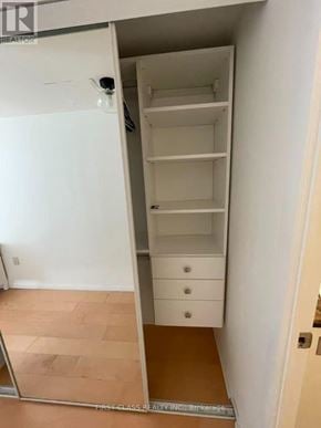 Toronto (Bay Street Corridor) condo for rent - A white closet with shelves and drawers is open to a room with wooden floors.