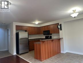 Whitby (Taunton North) townhouse for rent - A kitchen with wooden cabinets and a stainless steel refrigerator.