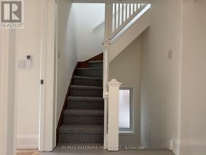 Toronto (North Riverdale) triplex for rent - A staircase with a white railing and a grey carpet.