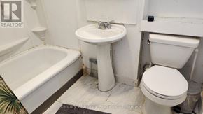 Oshawa (Central) multi-family for rent - A white toilet sits next to a sink in a bathroom.