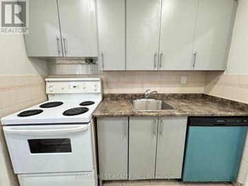 Mississauga (Malton) condo for rent - A white stove and oven in a kitchen with white cabinets and a granite counter.